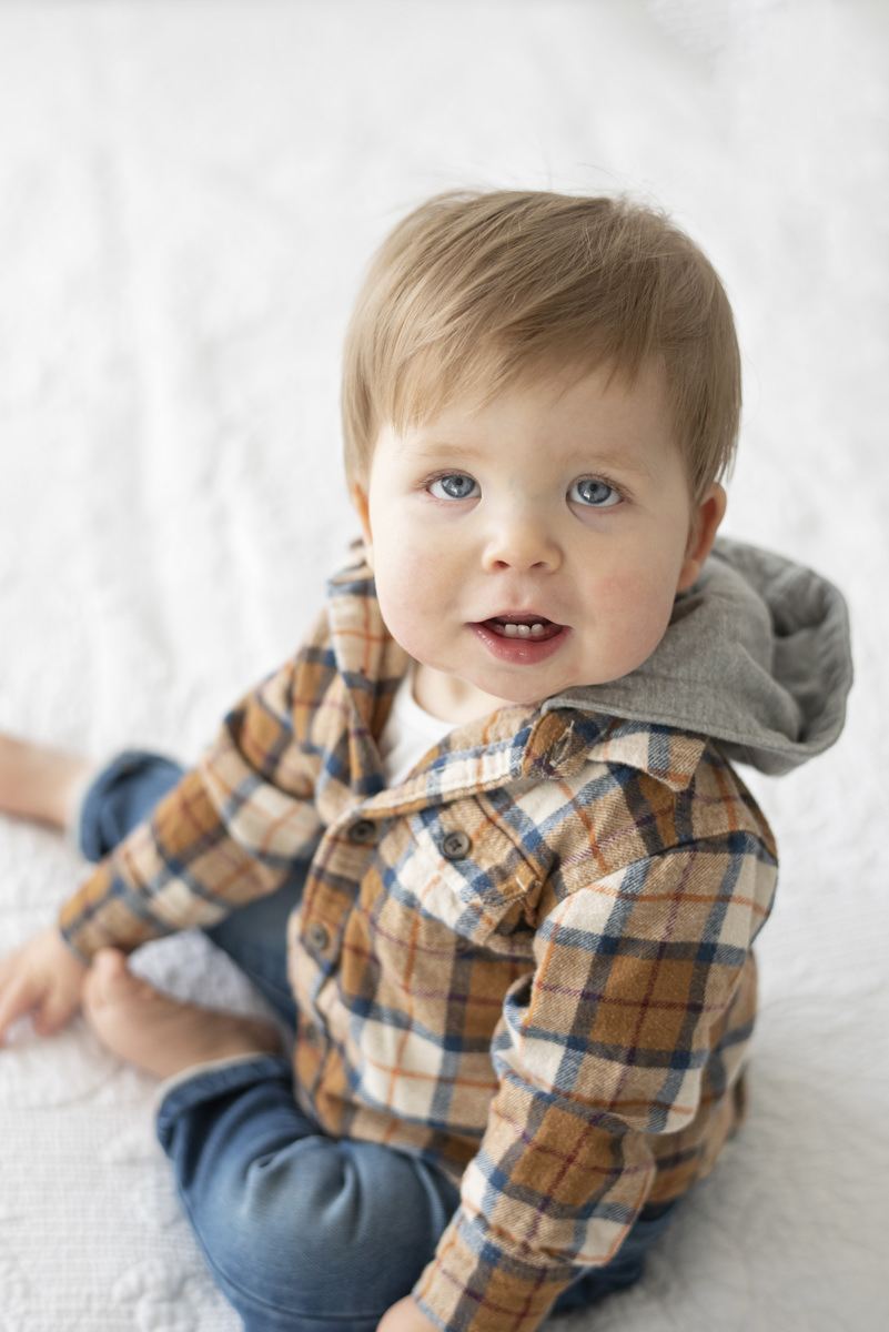 One year old boy wearing an orange and blue plaid shirt with a hood