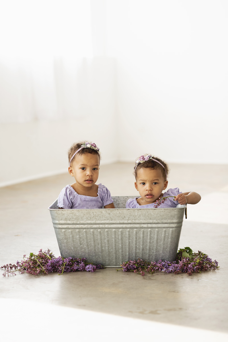 Twin two year old black girls in a lilac milk bath