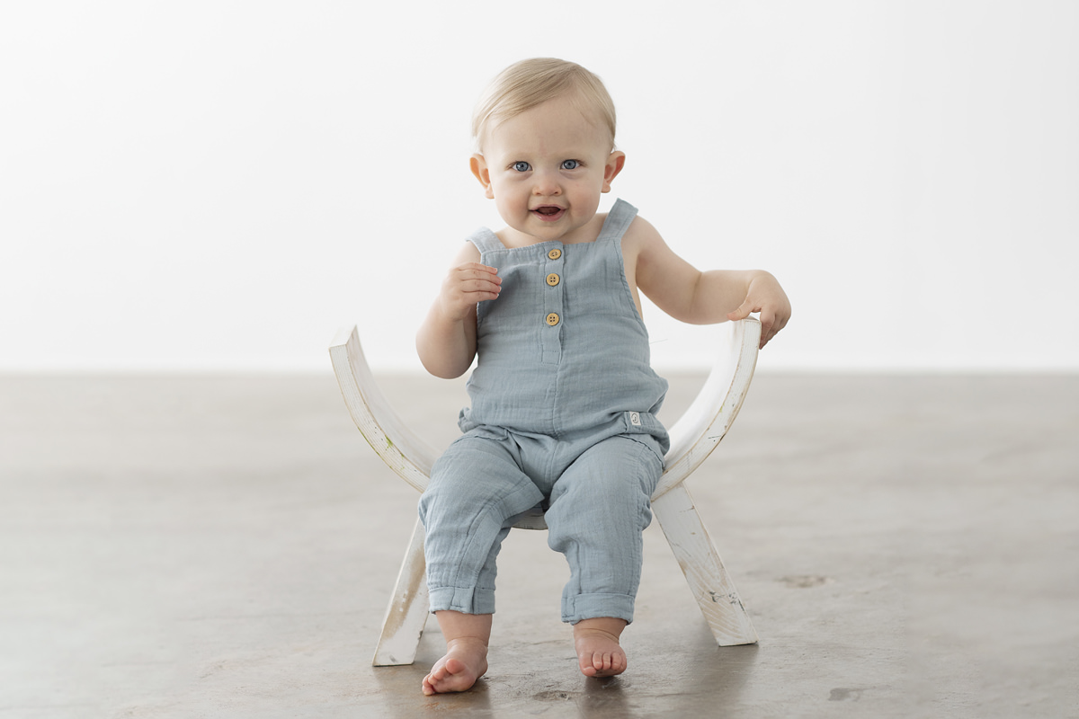 One Year Old Boy Studio Pictures Natural Light Wearing Blue Cotten Overalls Without a Shirt