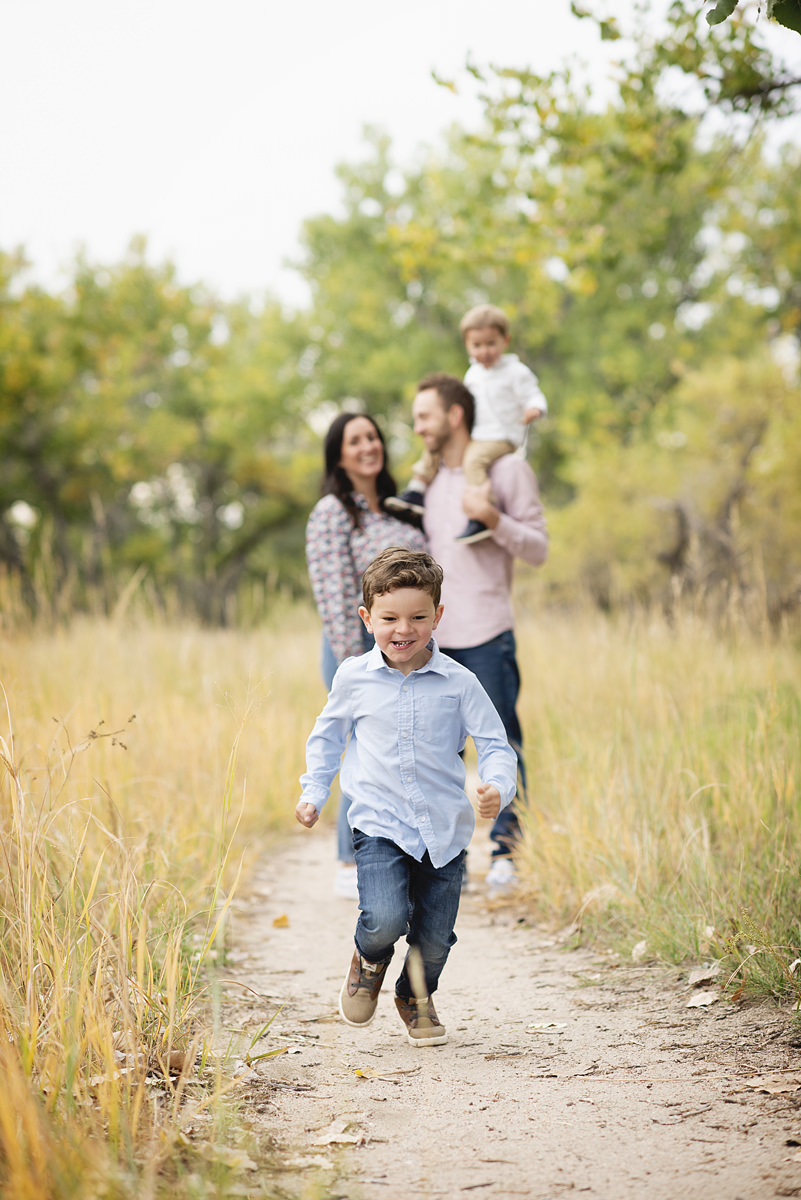 five year old boy running on a path with his family behind him