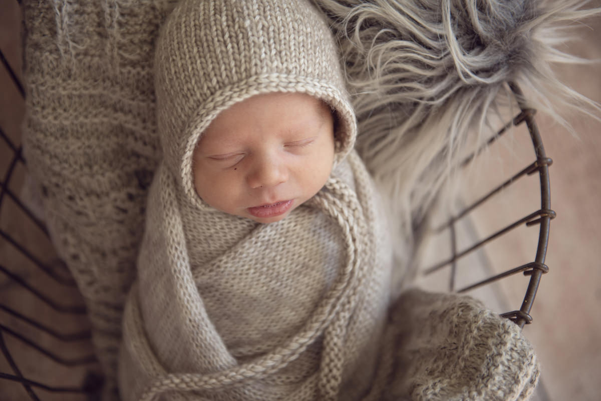 In-home newborn picture of a baby boy in a wire basket wearing neutral earth tone colors in Parker, Colorado