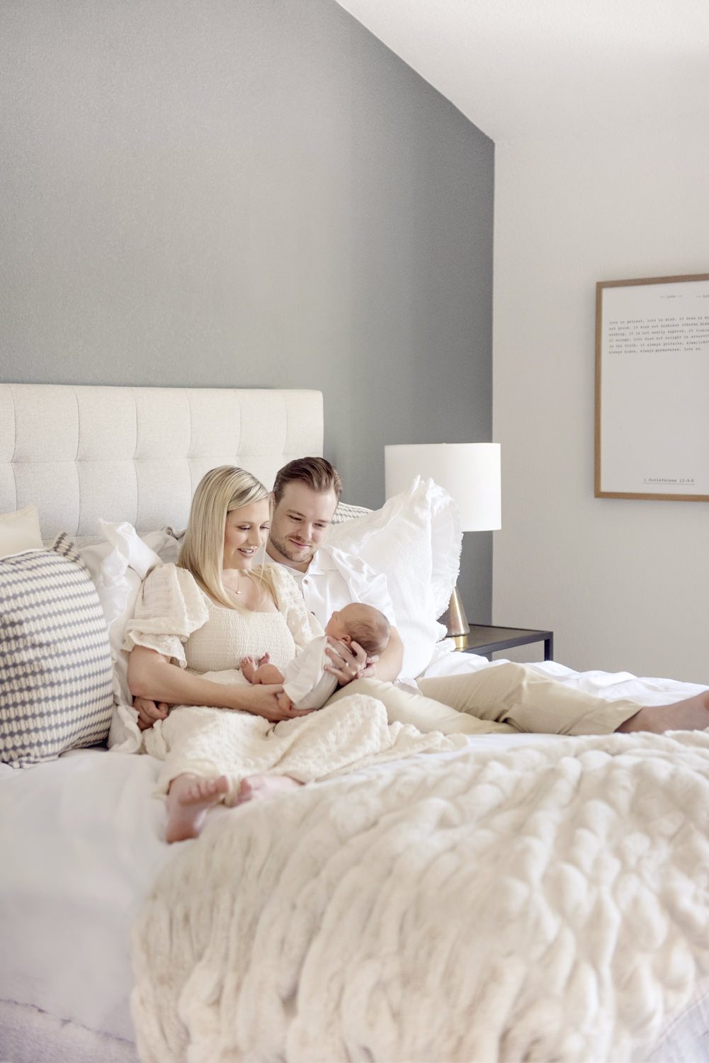 bedroom lifestyle picture of a mom and dad on a bed with their newborn