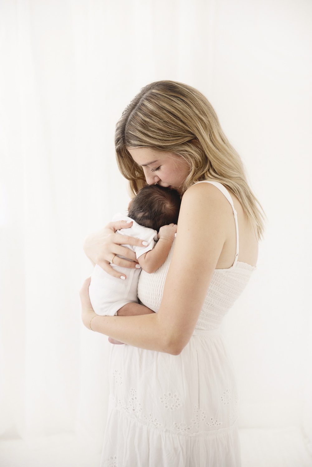 studio photo of a young mom missing the top of her newborn baby's head taken by Parker, CO photographer Jamie Herrera