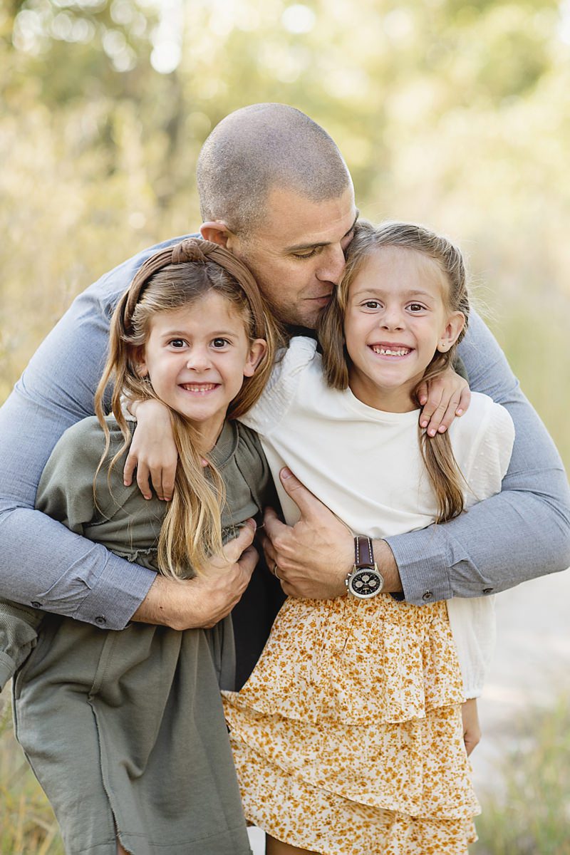 Dad kissing his two girls hugging them, Parker family photography