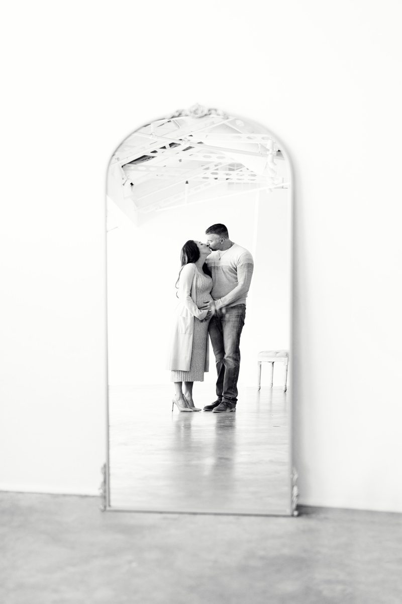 Black and white mirror with the reflection of a pregnant couple kissing; Parker maternity photographer