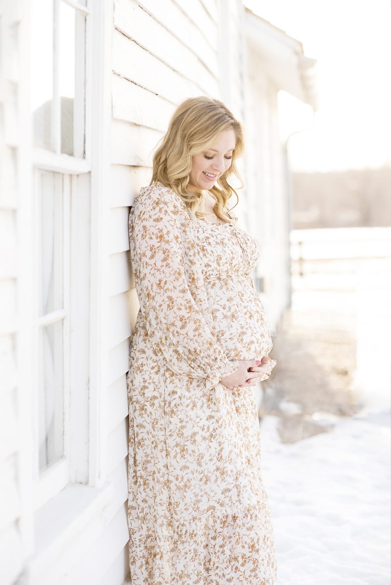Pregnant mom holding her belly and looking down; Parker maternity photographer