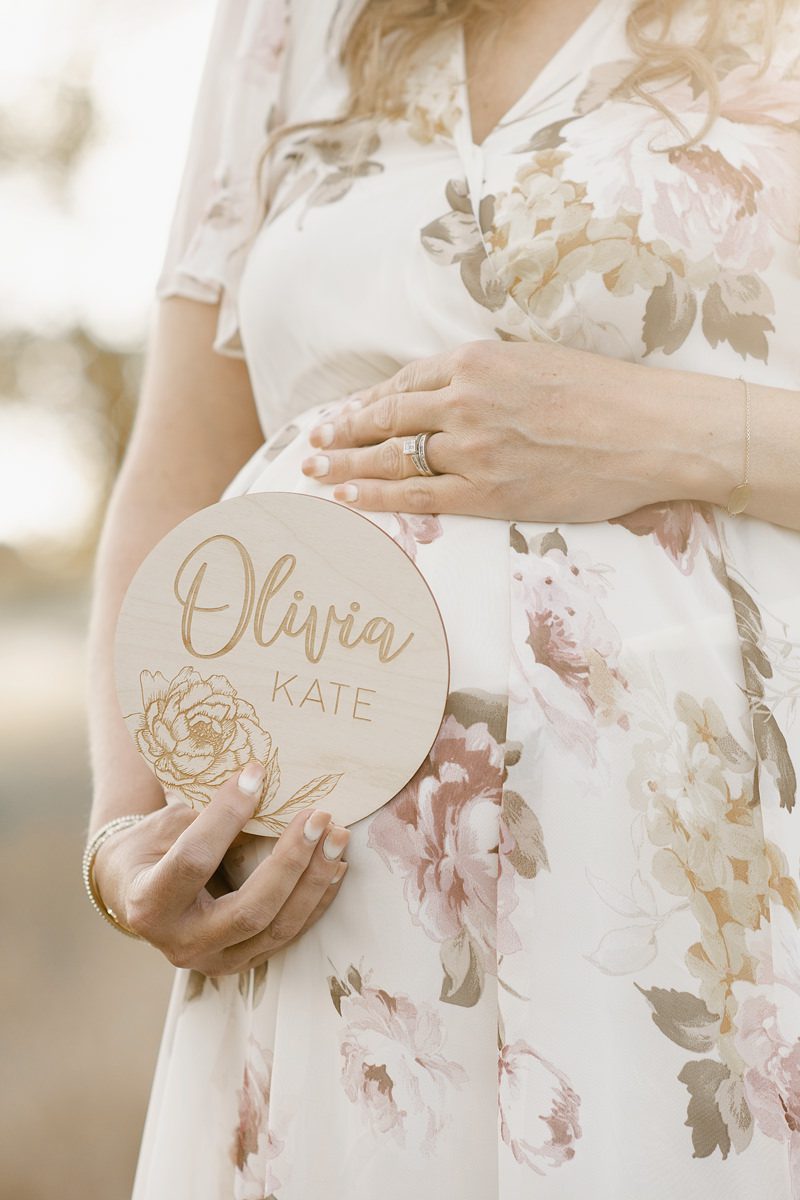 Pregnant mom holding a sign with her baby's name on it