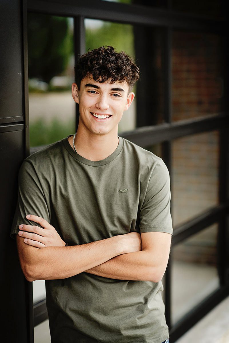 Guy leaning against a black garage door with windows for his Parker senior pictures