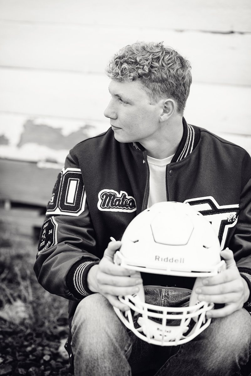 Boy with football helmet and letter jacket senior pictures in Parker, Colorado