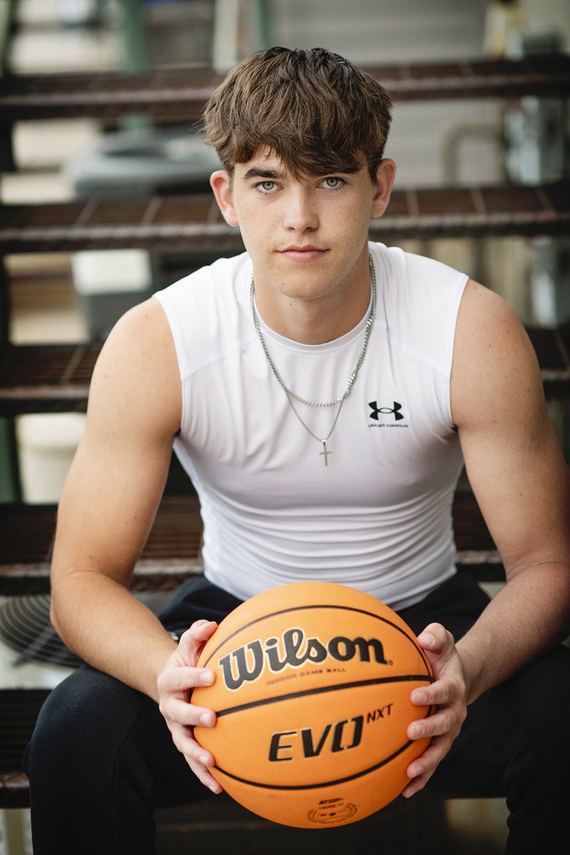 High school Parker senior pictures of a guy holding a basketball sitting on steps