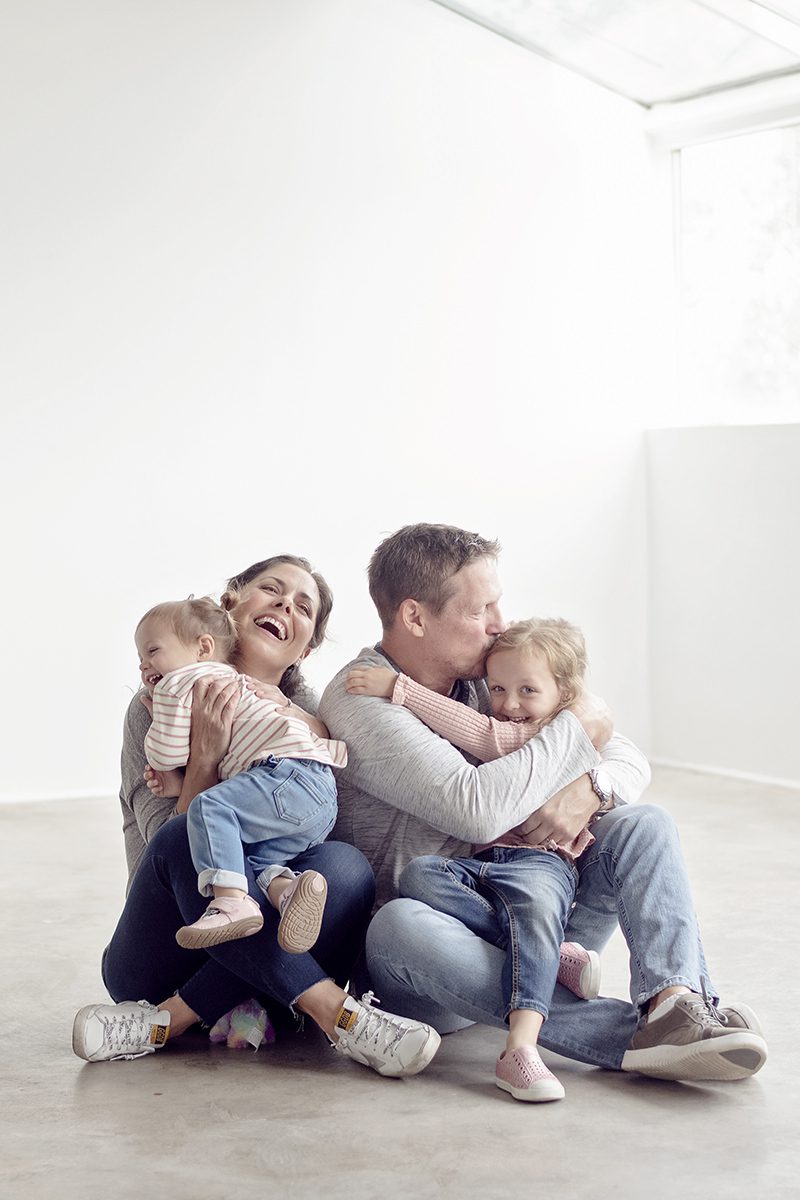 family sitting on the ground snuggling in a studio with cement floors and white walls