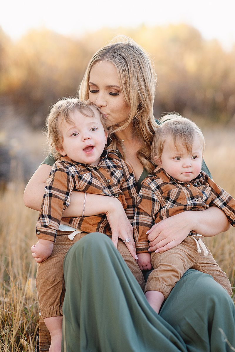 Mom kissing her toddler twin boys on the head
