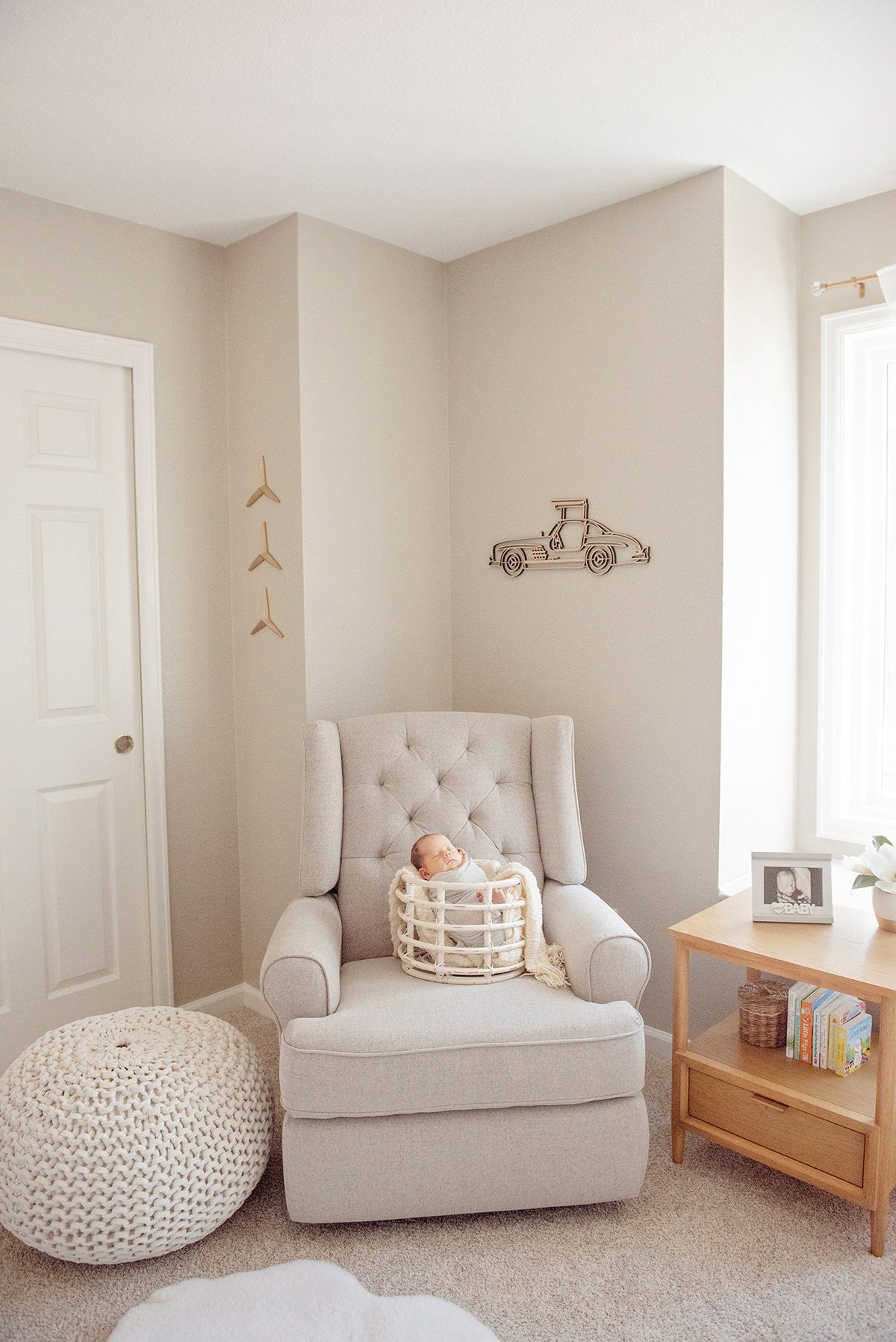 aurora newborn photographer capturing a baby in a basket on a cozy nursery chair with soft neutral decor and natural window light